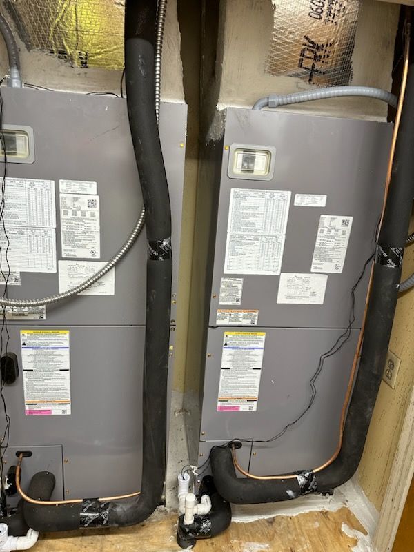 Two air conditioners are sitting next to each other in a room.