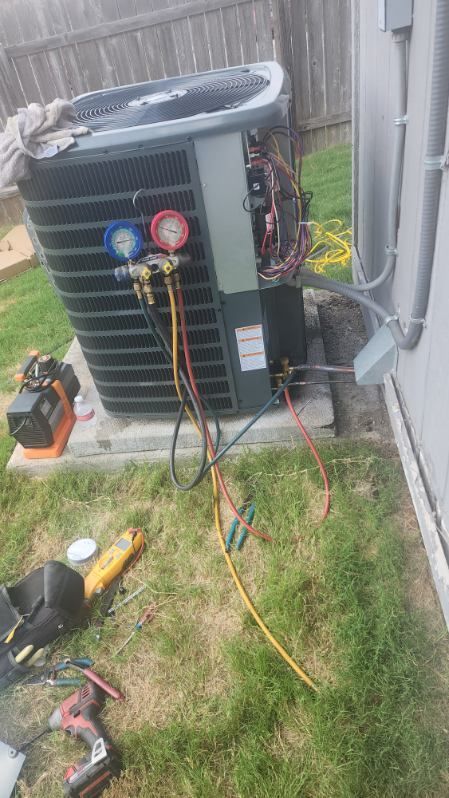 An air conditioner is being repaired in the backyard of a house.