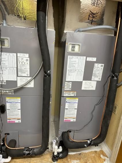 Two air conditioners are sitting next to each other in a room.