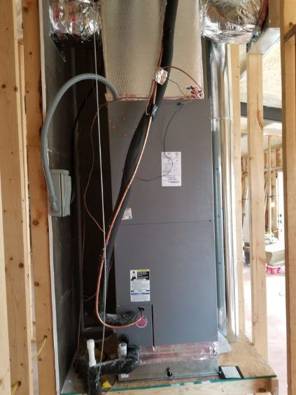 An air conditioner is being installed in a room in a house under construction.