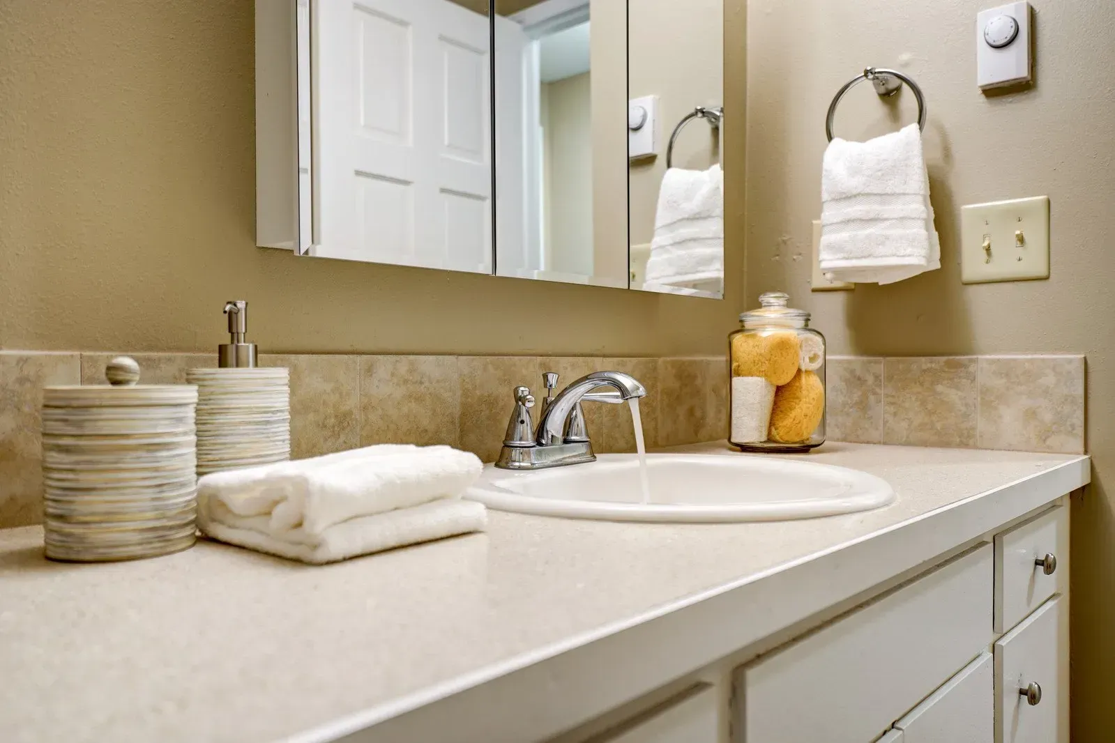 Bathroom with a sink, white countertop, mirror, and towels.