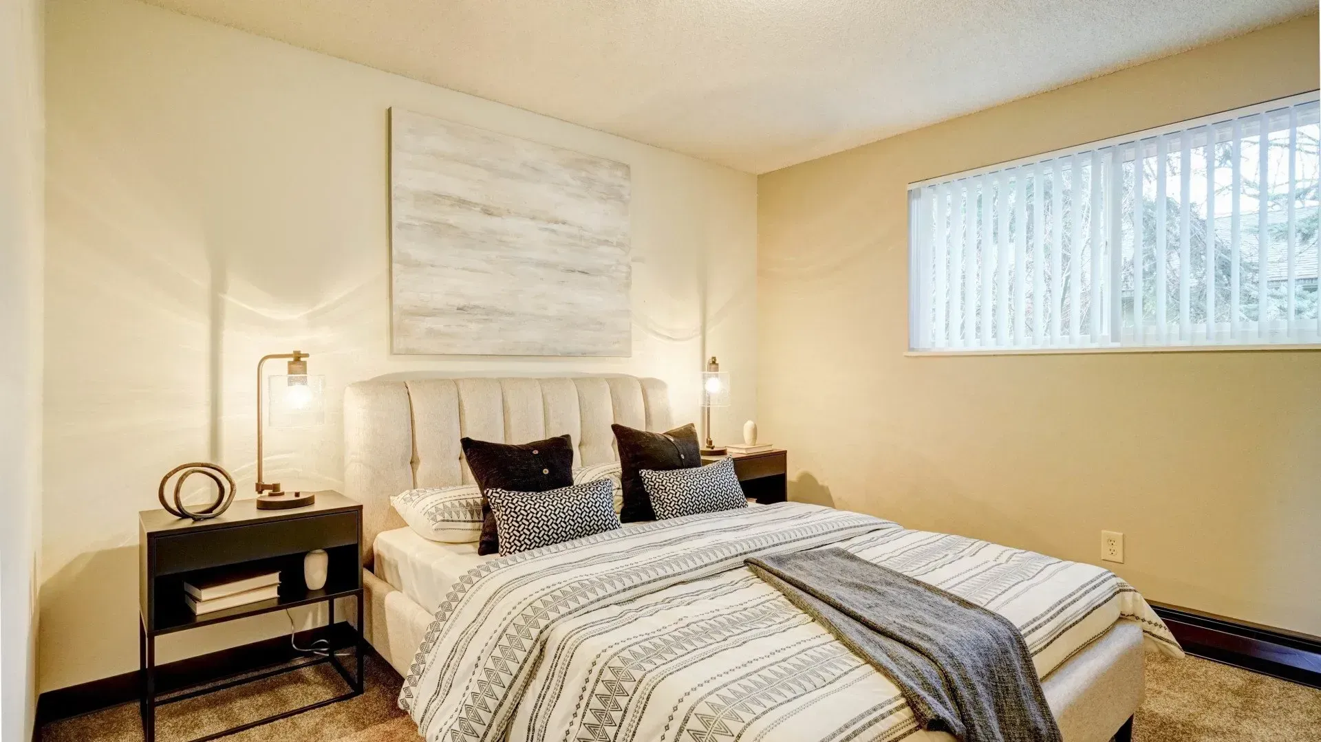 Bedroom with bed, nightstands, artwork, and a window with blinds.