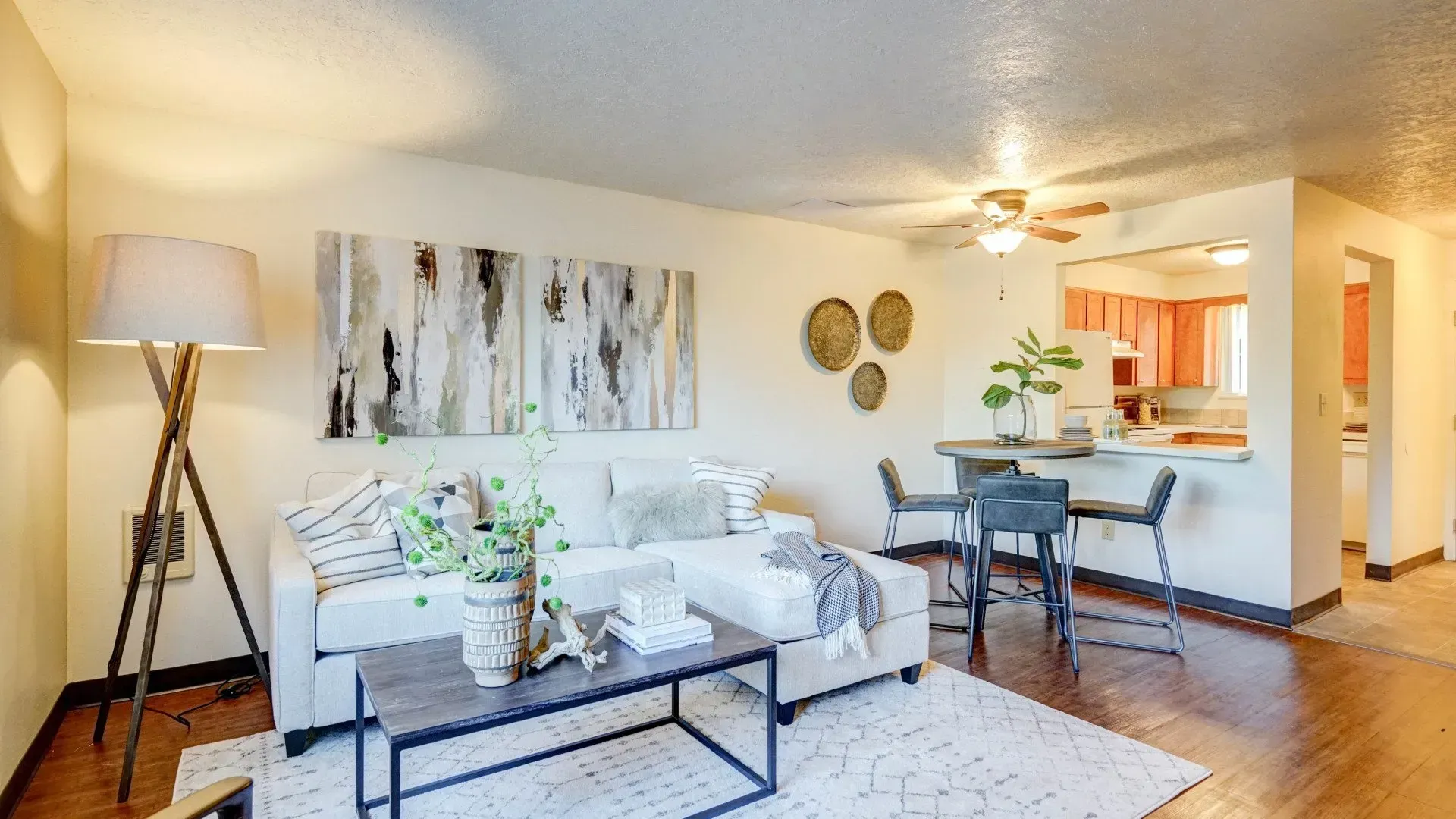 Living room with a white couch, wooden floor, and a small dining area.