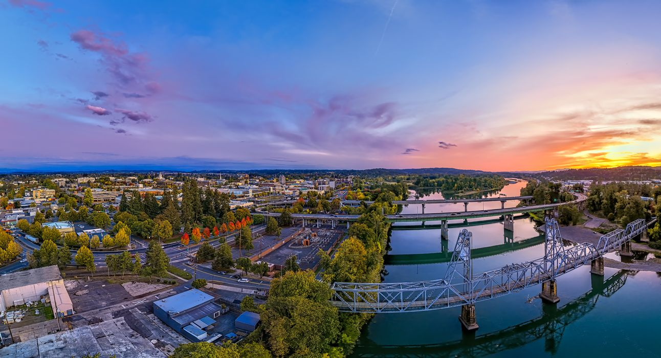 Aerial view of a city with bridges over a river, vibrant sunset sky.