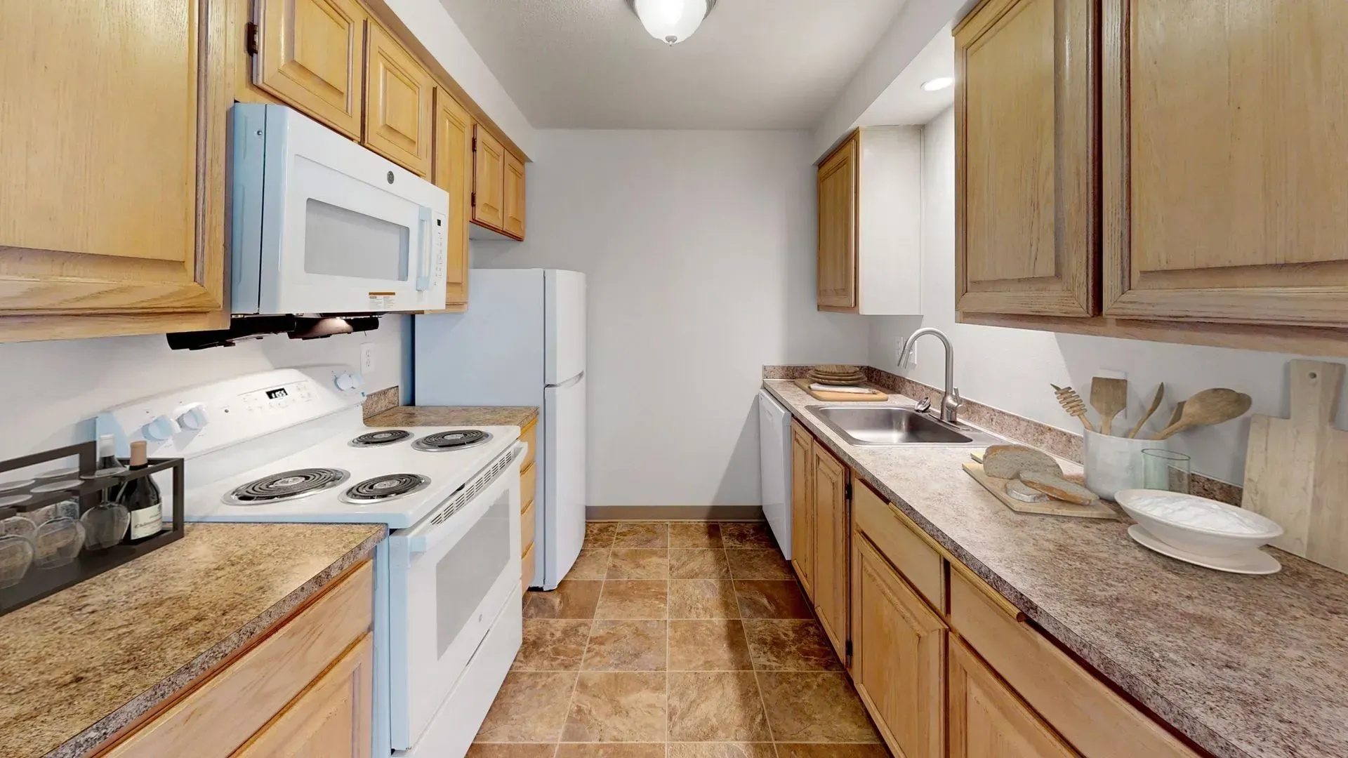 Kitchen with wood cabinets, white appliances, and speckled countertops.
