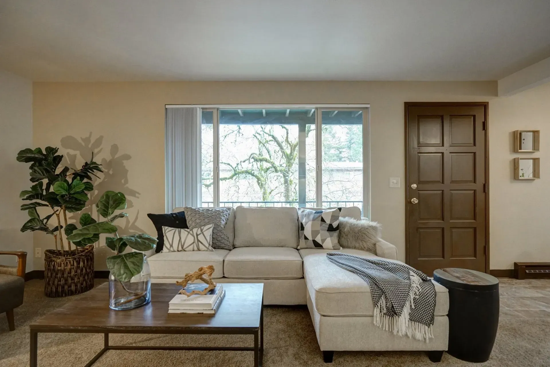 Living room with beige sectional sofa, coffee table, and large window.