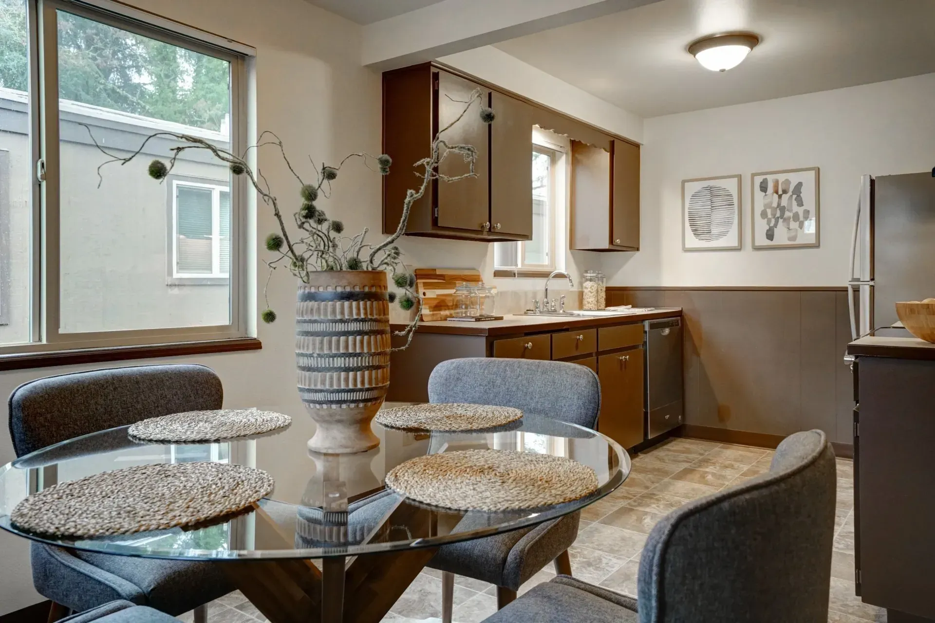 Kitchen with dining table, dark cabinets, stainless steel appliances, and two small art prints on the wall.