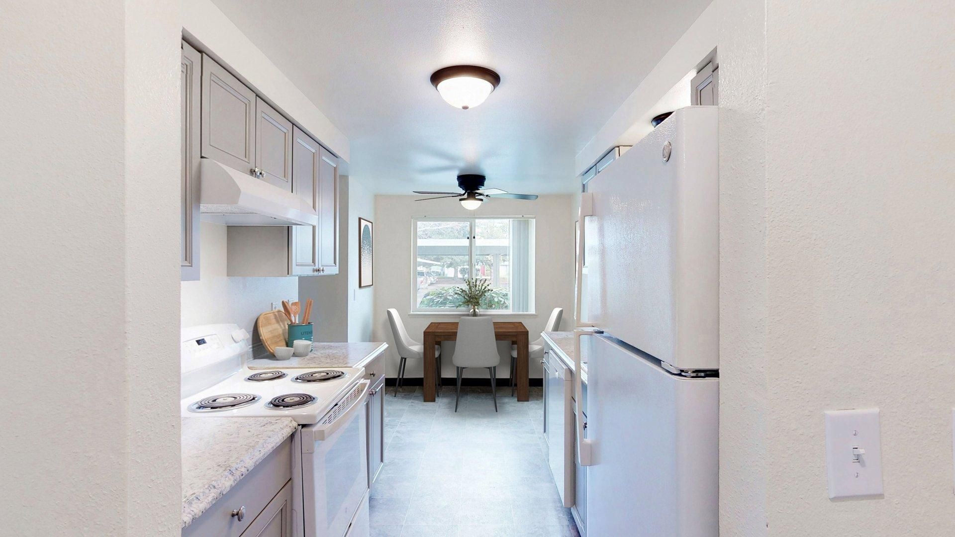 Kitchen with stove, cabinets, refrigerator, and dining area with table and chairs.