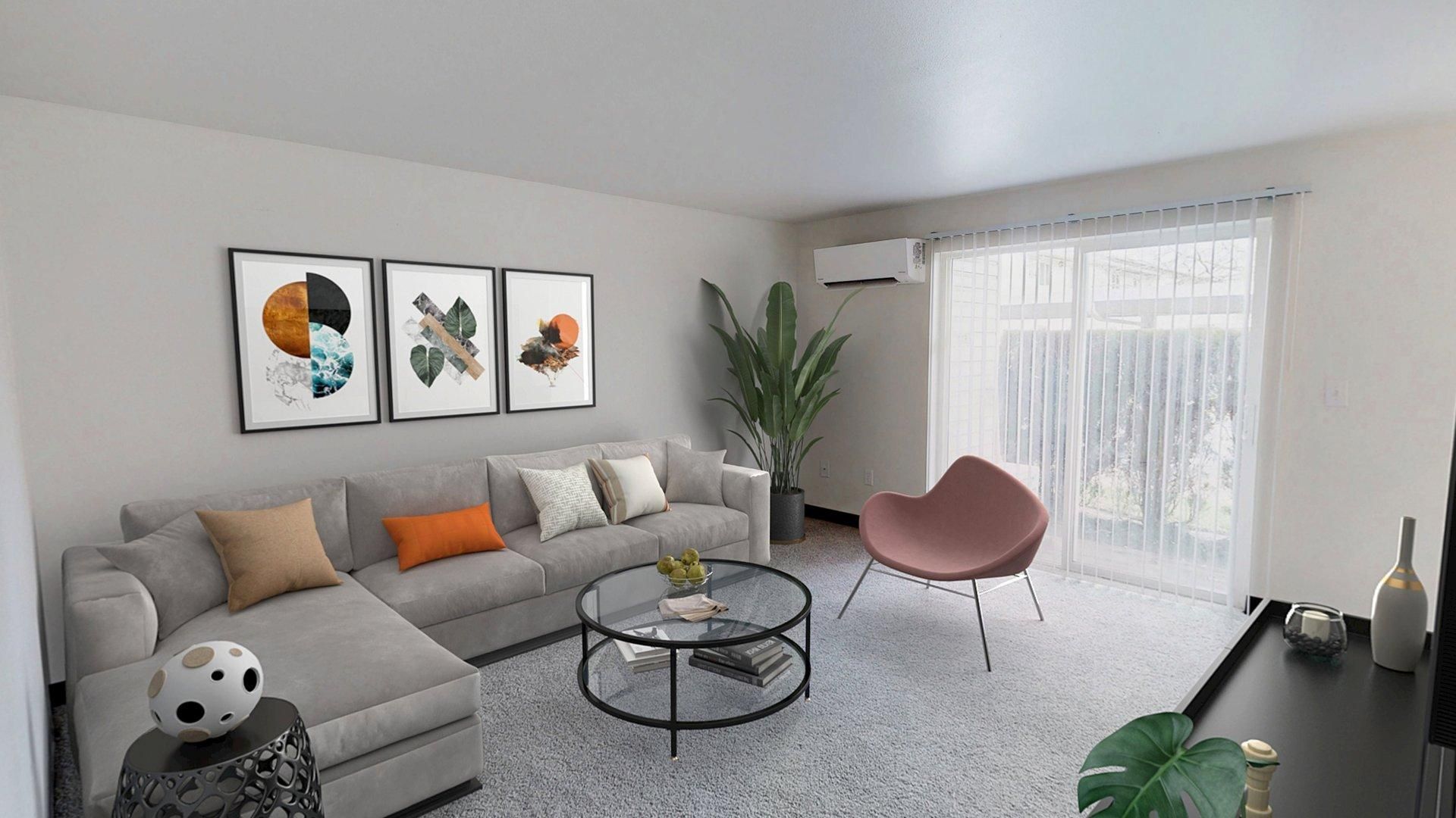 Living room with gray sofa, art prints, round glass coffee table, and pink chair.