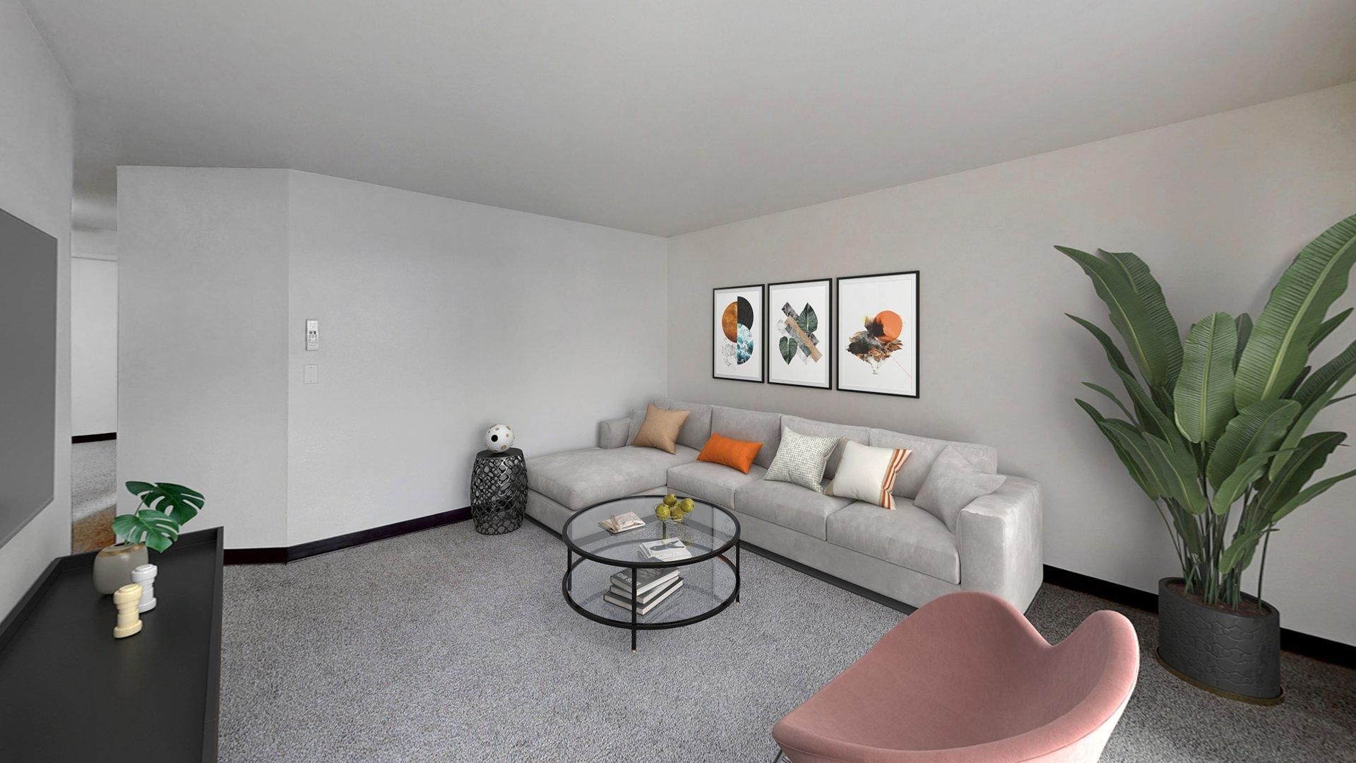 Living room with gray sofa, coffee table, art, pink chair, and large plant.