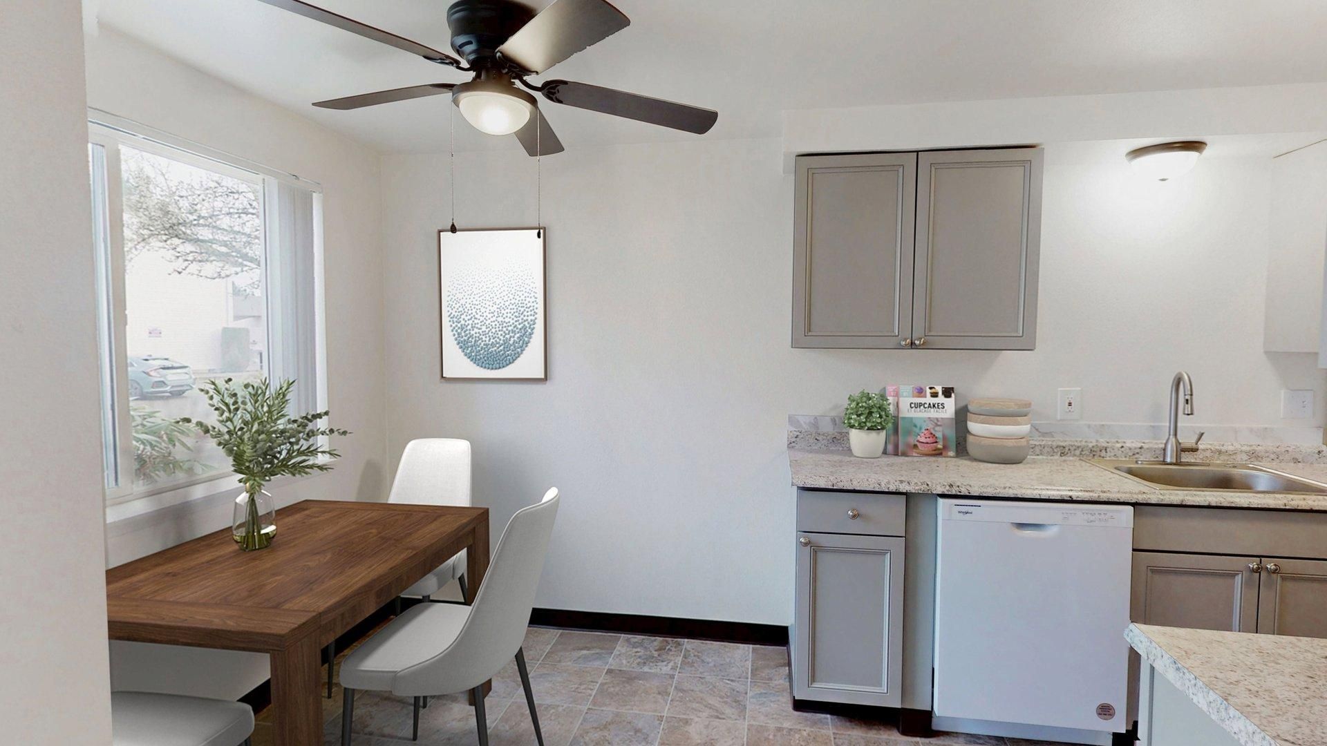 Kitchen area with dining table, cabinetry, and window.