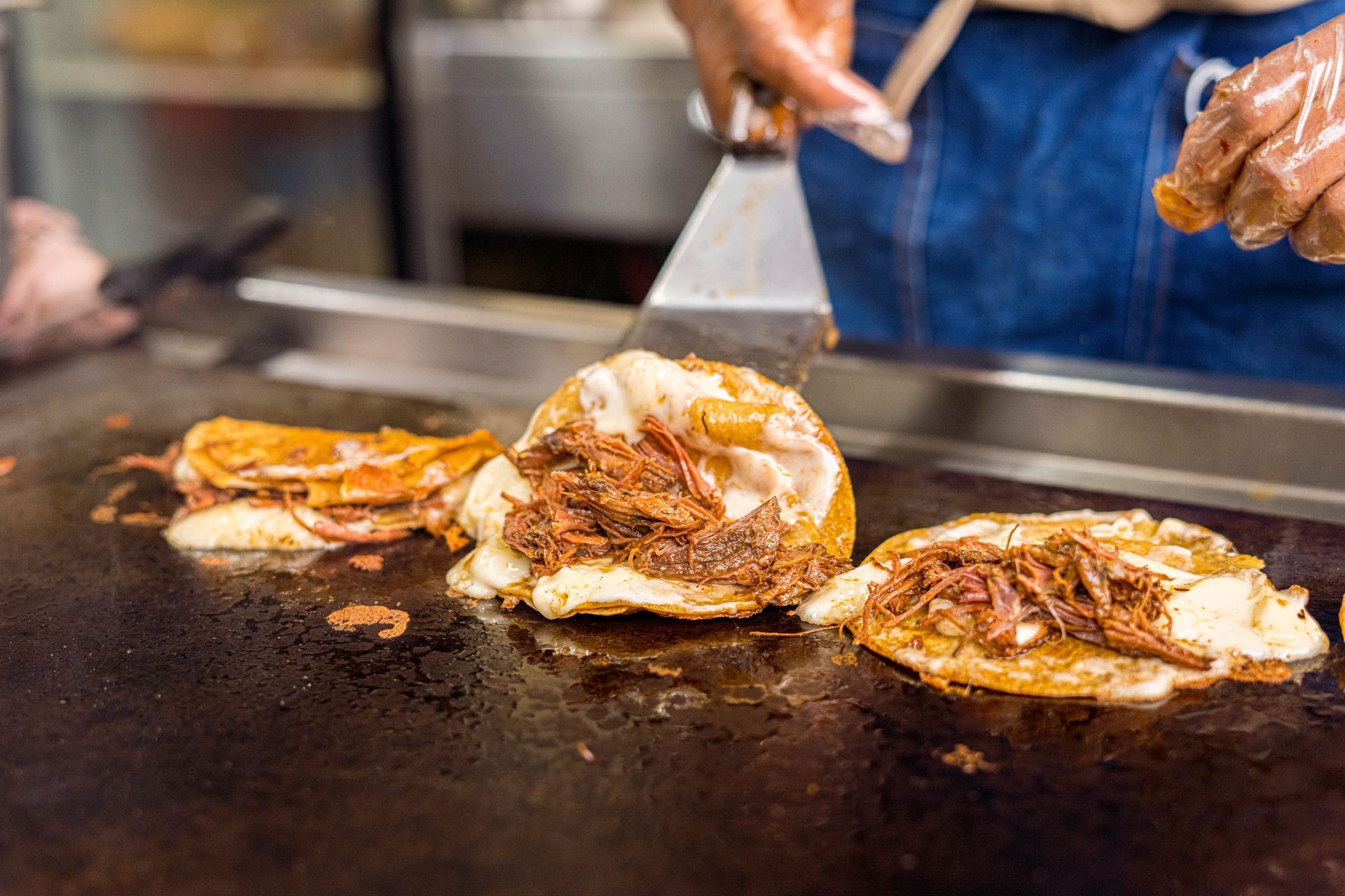 Sandwiches on a hot griddle, being flipped. Melted cheese, dark meat.