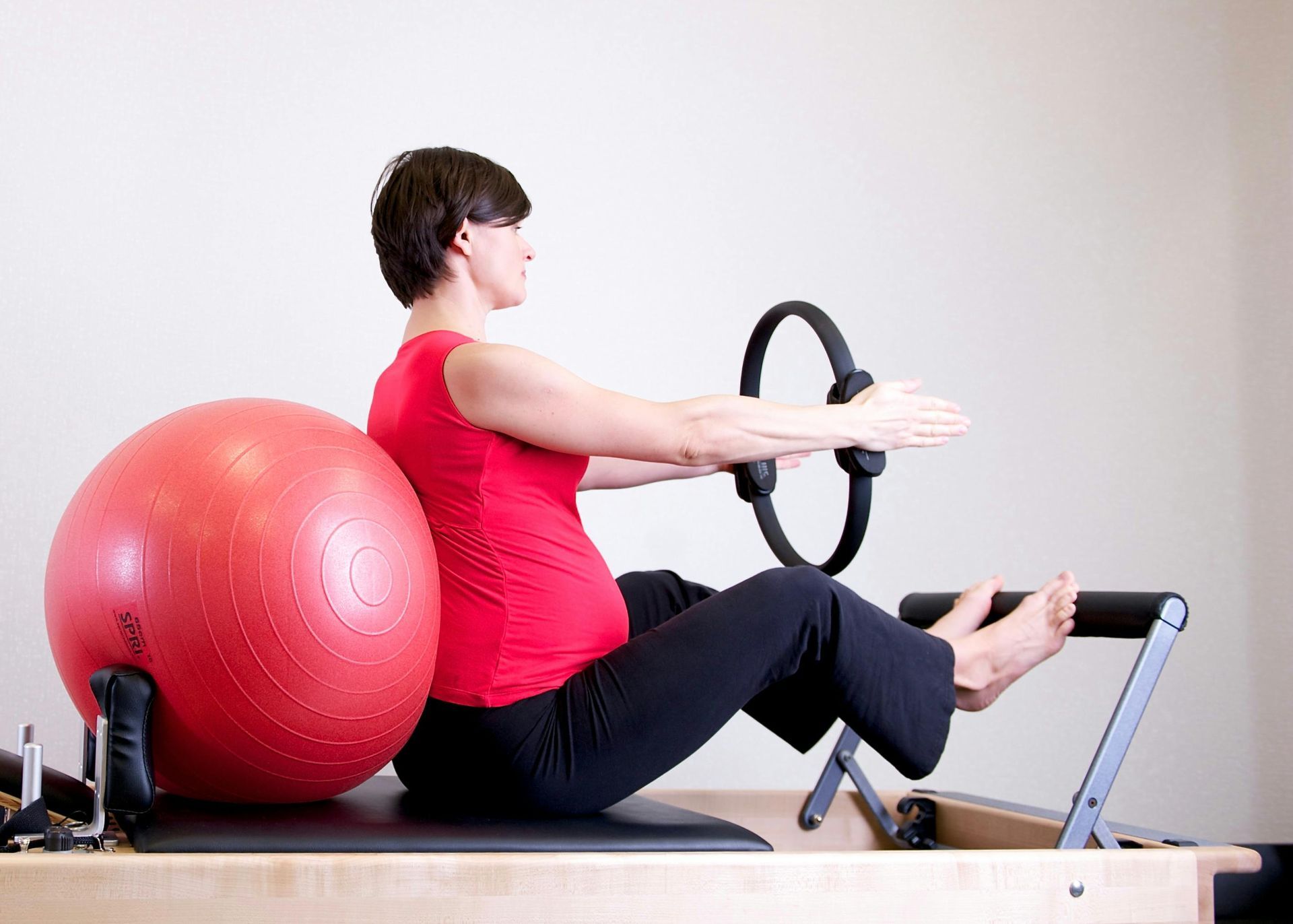 A Pregnant Woman Is Doing Pilates on A Pilates Machine — Burwood Back Pain in Strathfield, NSW