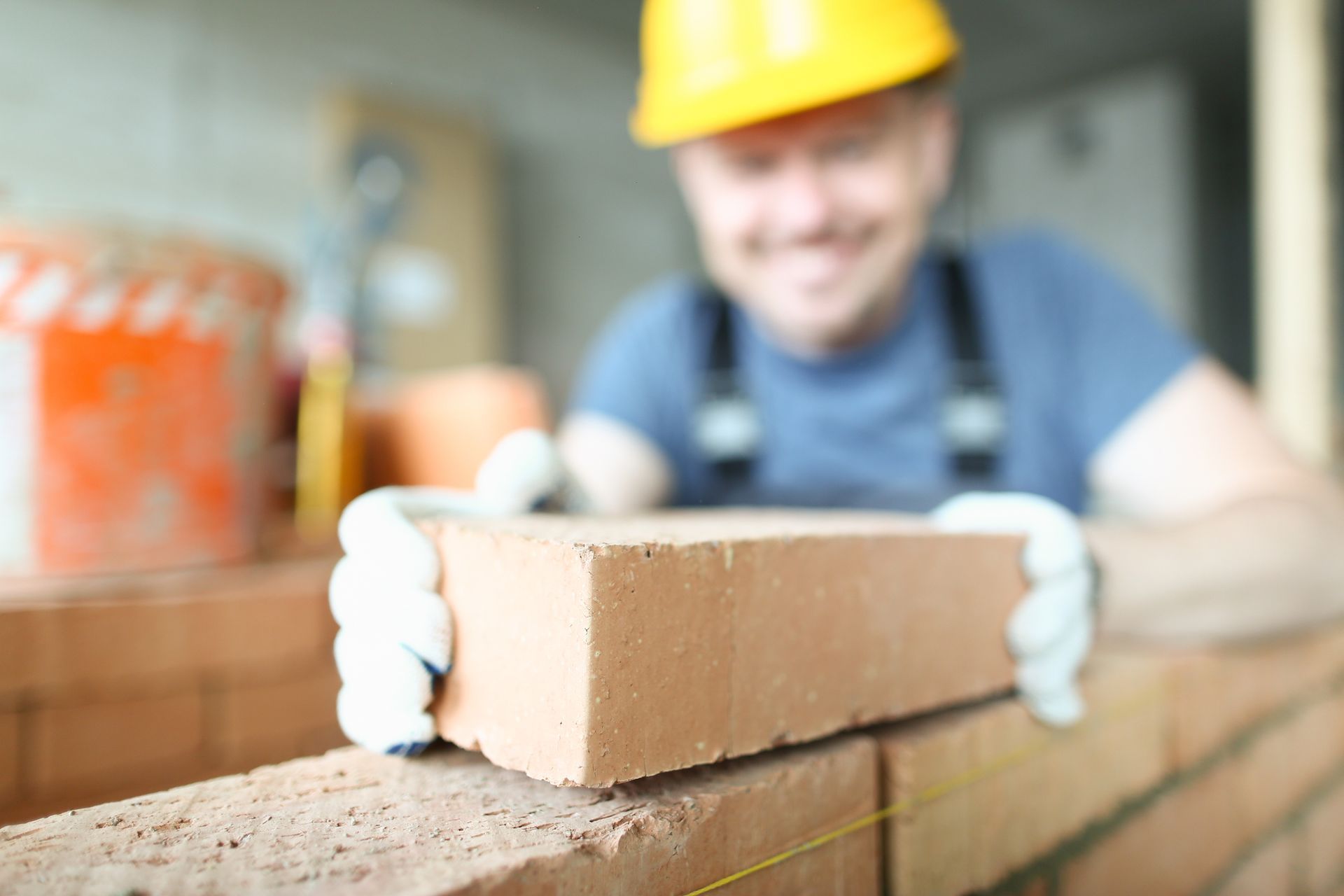 Male smiling builder puts make brickwork