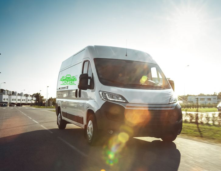 White van driving on a road in sunlight; residential neighborhood— FNQ Freight & Logistics In Portsmith, QLD
