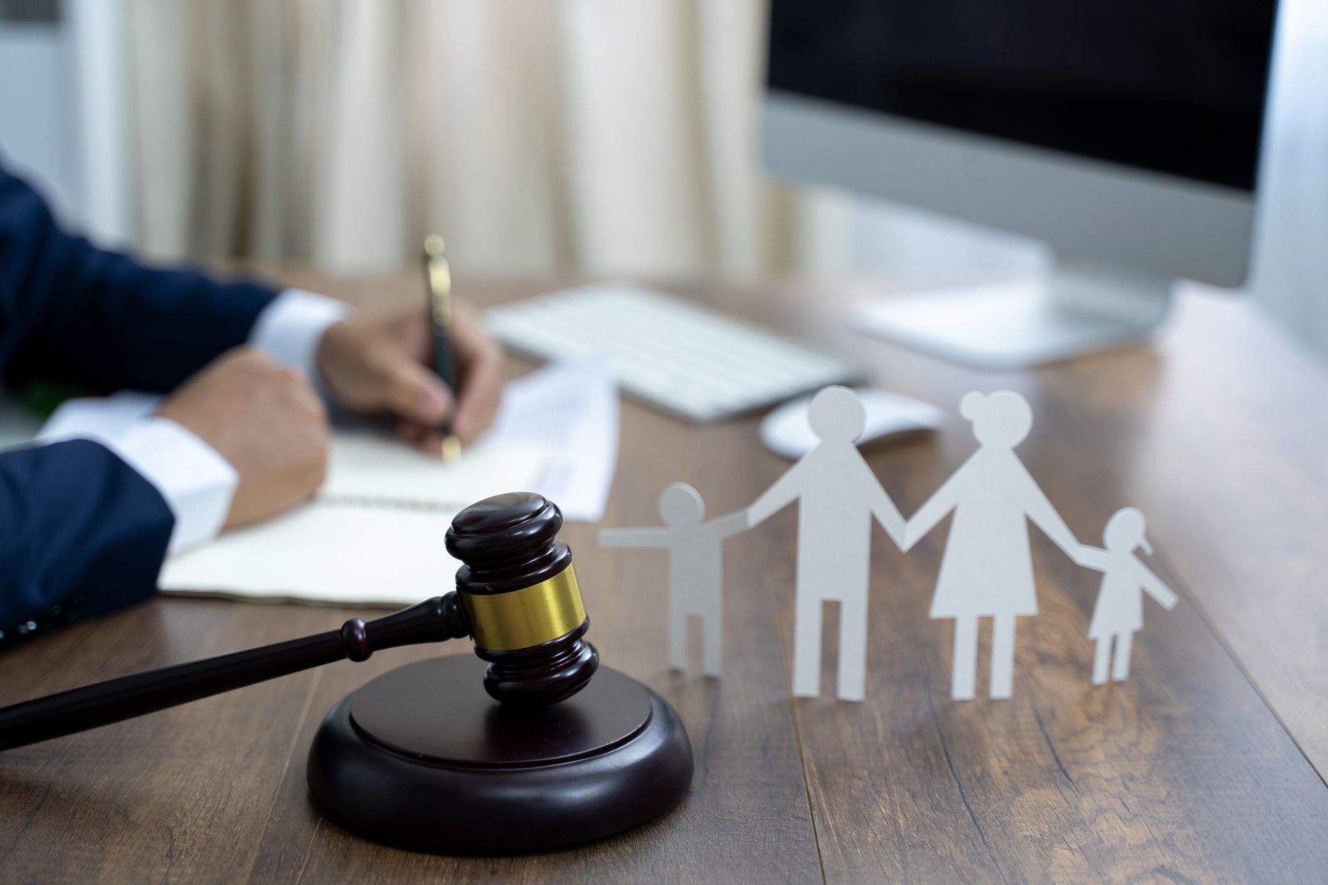 A gavel, paper family cutout, and family attorney in Kansas City, MO, signing legal documents in McE