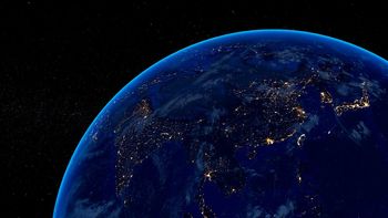 Earth at night showing illuminated continents against a starry black sky.