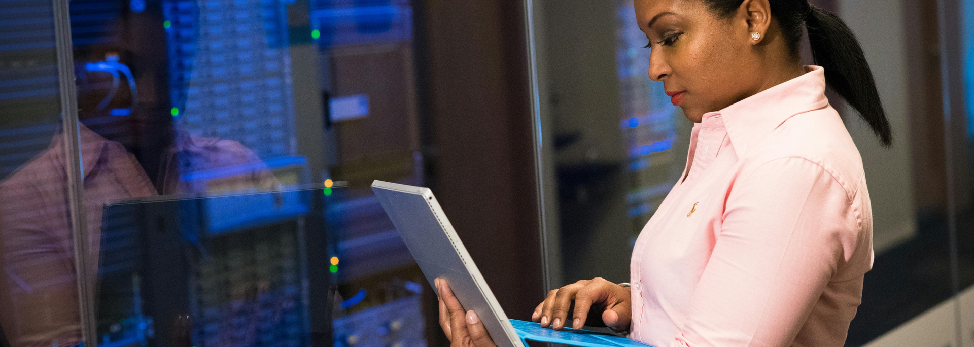 Picture of a person looking at a laptop attached to a server. 