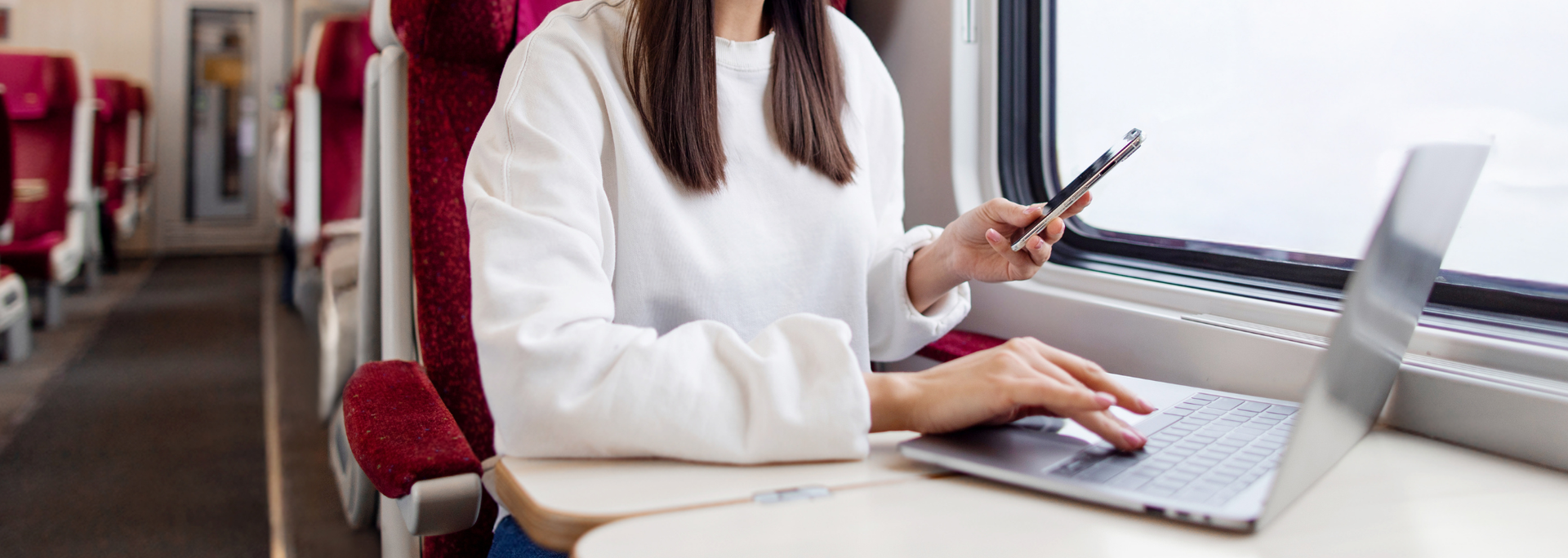Picture of a woman using her laptop on a train. 