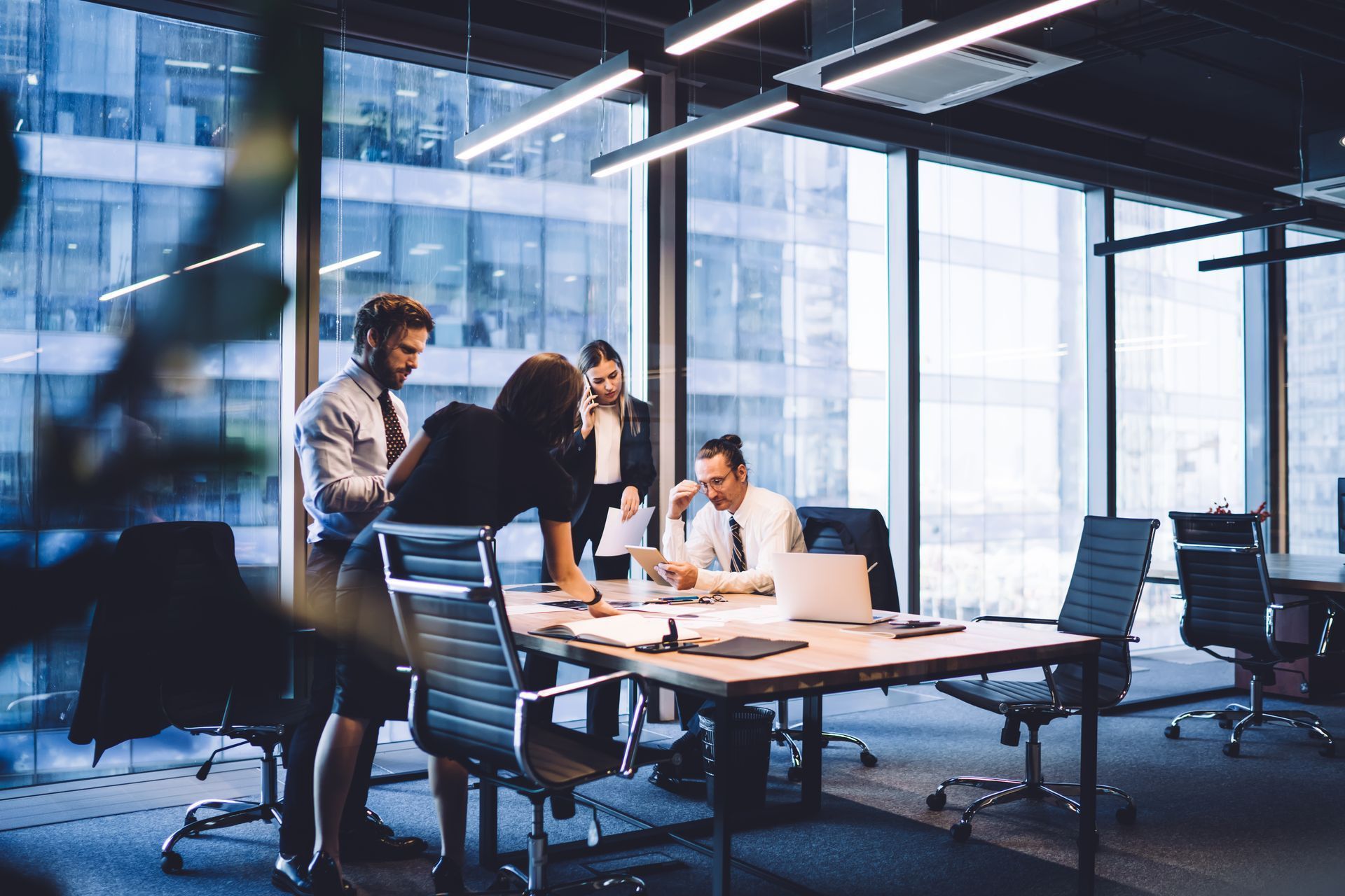Business team reviewing documents at a table in a modern office, with city views.