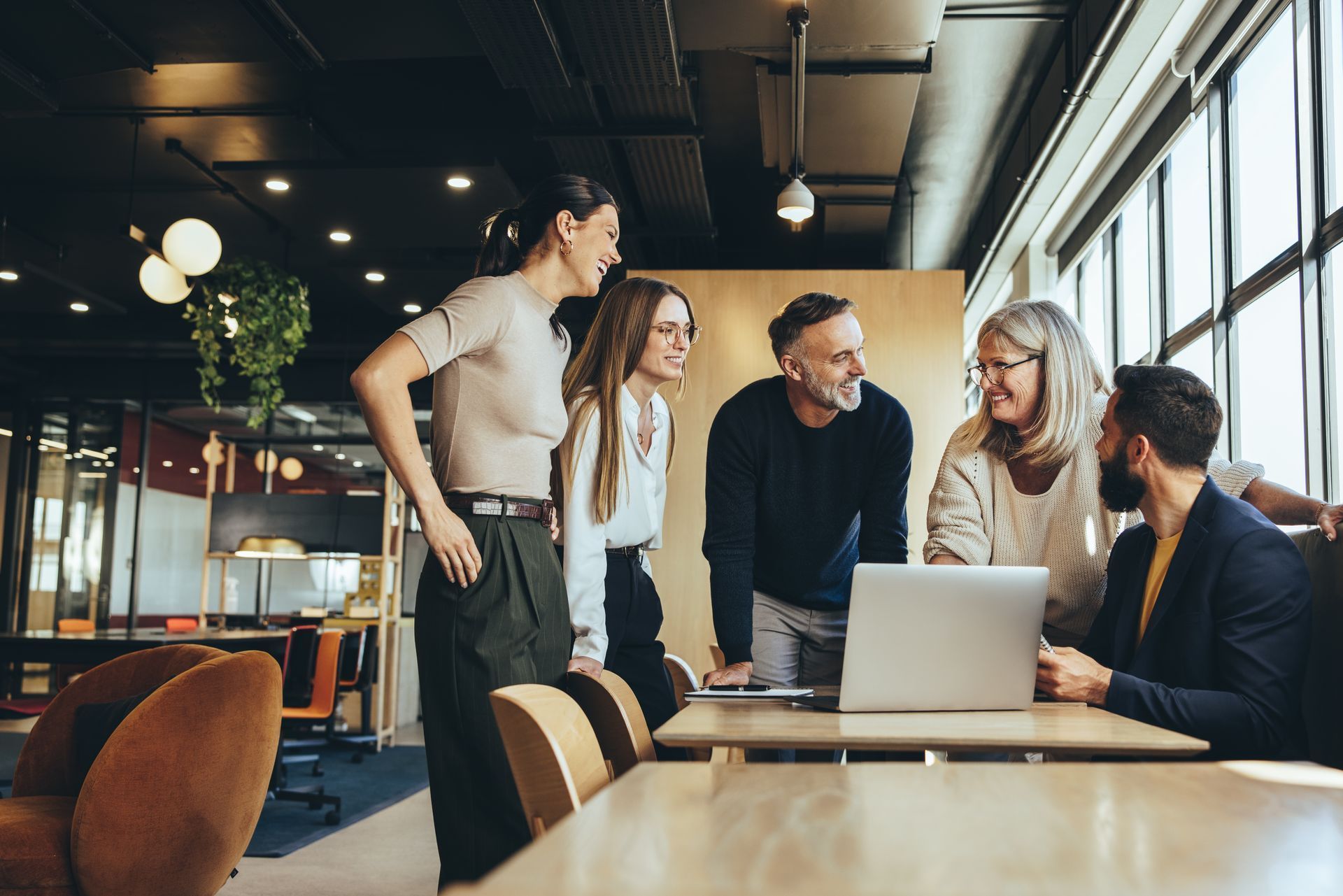 Group of people collaborating around a laptop in a modern office setting.