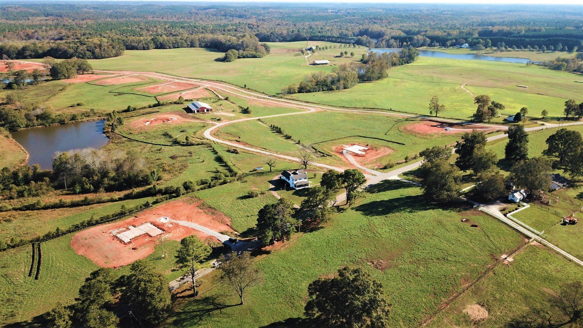 An aerial view of a lush green field with a lake in the middle.