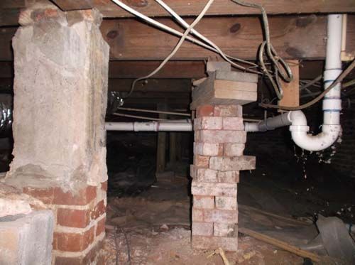 A basement with a brick chimney and a white pipe.