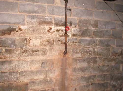 A brick wall with a pipe coming out of it.