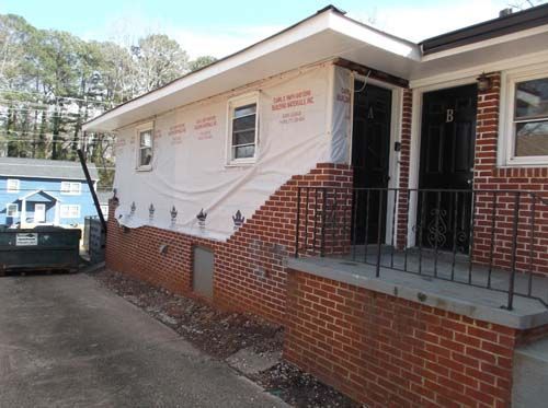 A brick house with a dumpster parked in front of it.