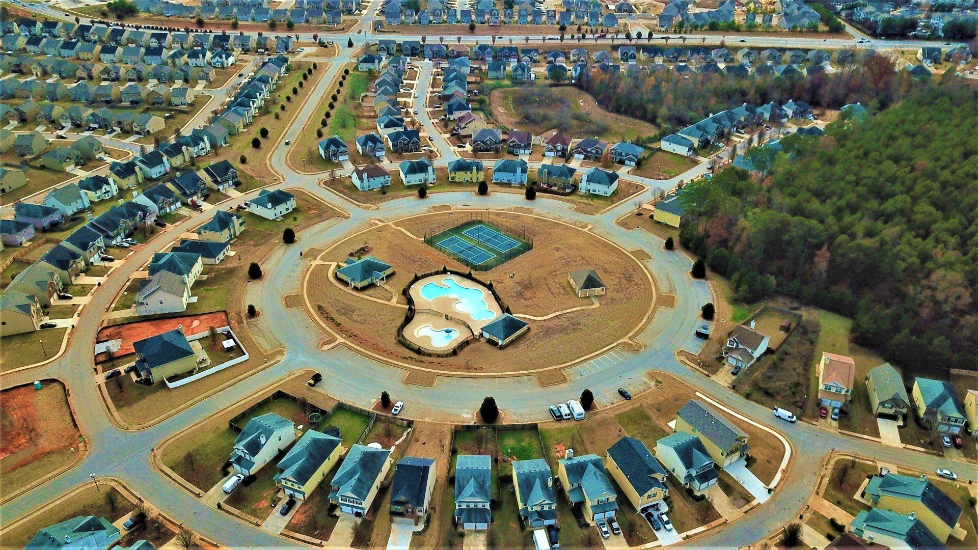 An aerial view of a residential area with a pool in the middle.
