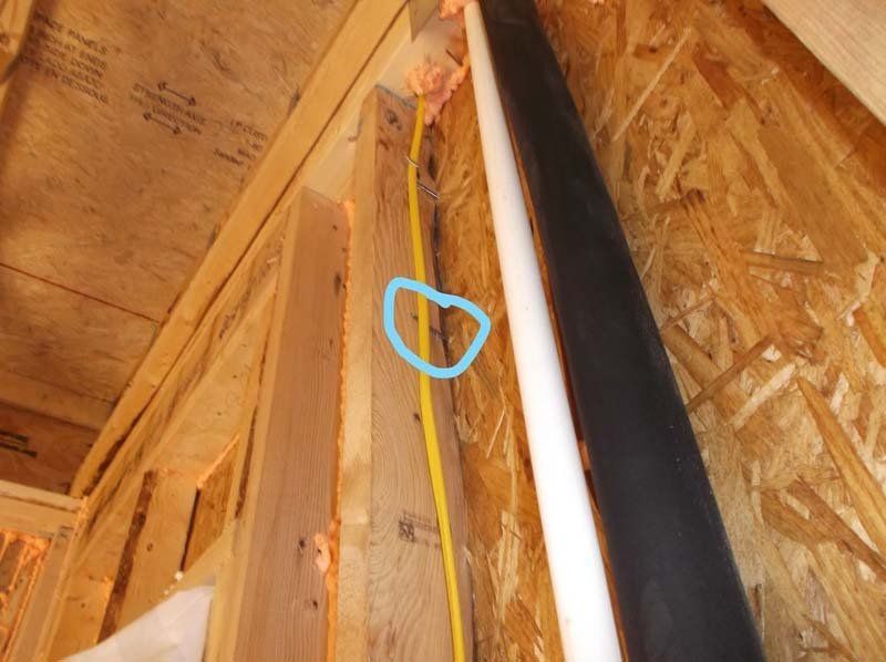 A blue circle is drawn on a wooden wall next to a white pipe.