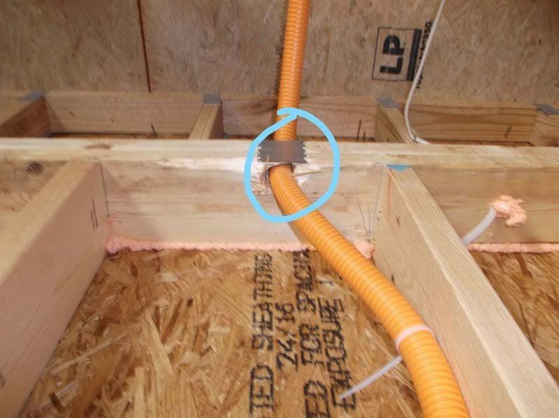 An orange pipe is connected to a piece of plywood that says ted shearhart
