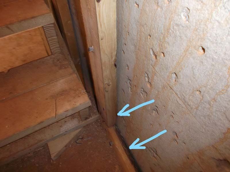 A close up of a wooden staircase with arrows pointing to holes in the wall.