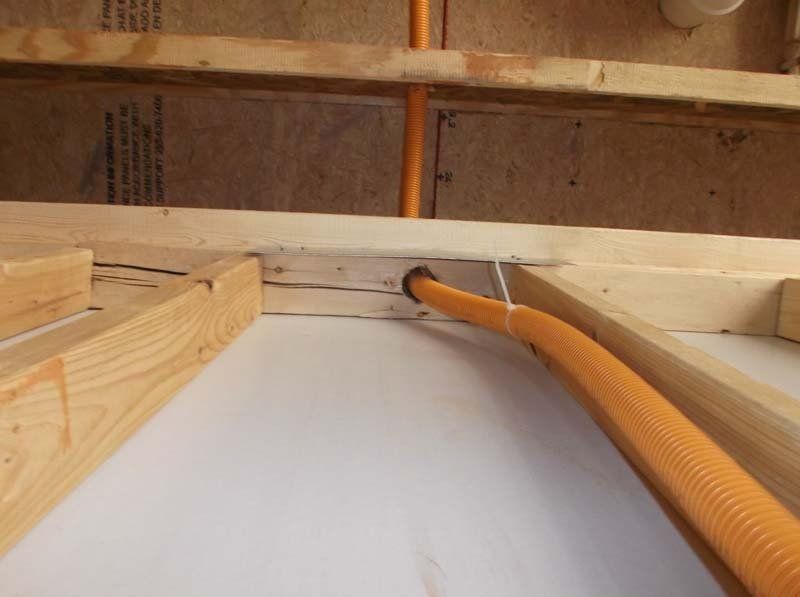 A yellow pipe is going through a hole in a wooden structure.