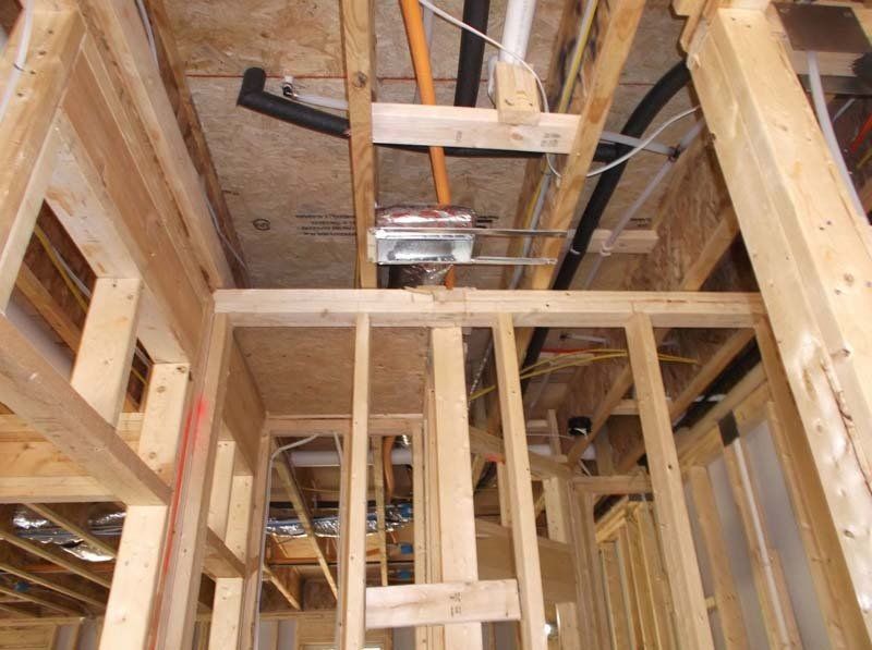 A wooden frame of a building with pipes and wires