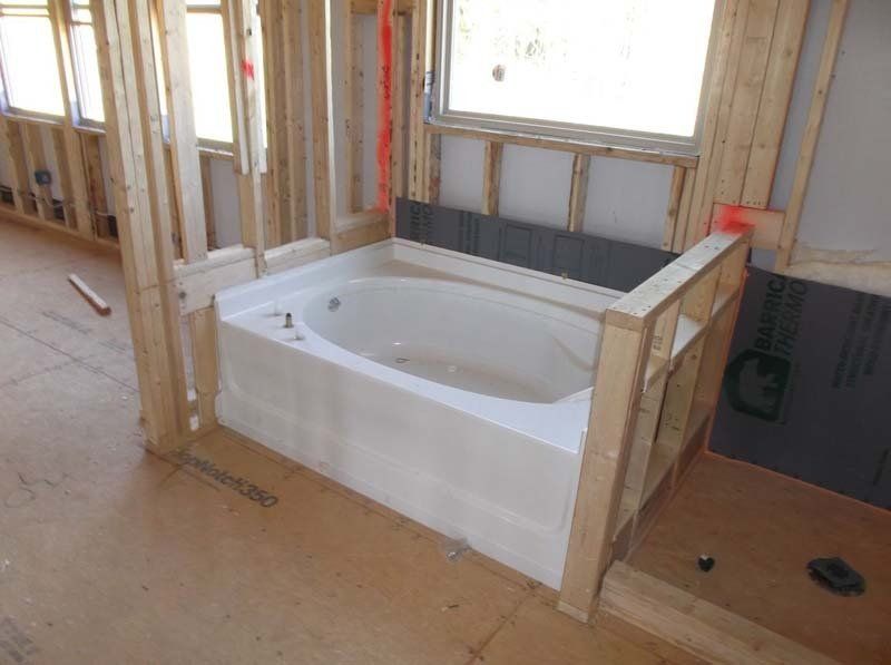 A bathtub is in the middle of a room under construction.