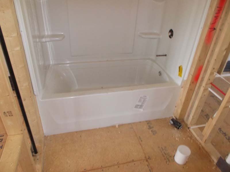 A white bathtub is sitting in a bathroom under construction.