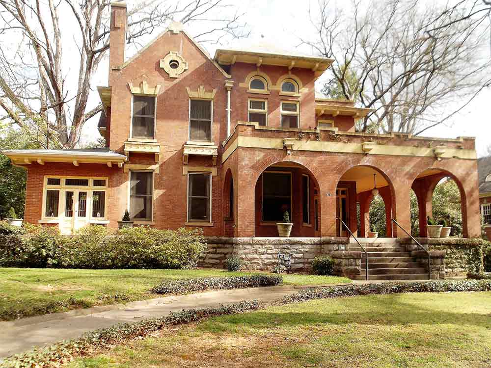 A large brick house with arched porches and stairs