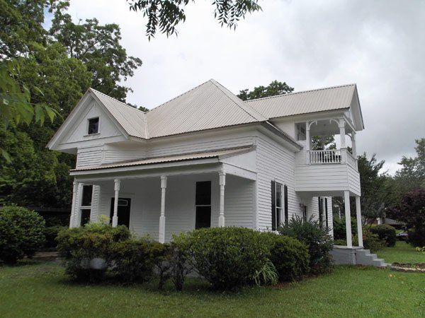 A white house with a metal roof and a porch