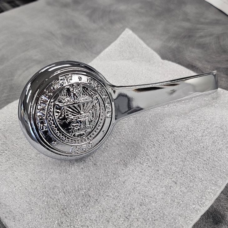 A man in a protective suit is painting a piece of metal in a factory.