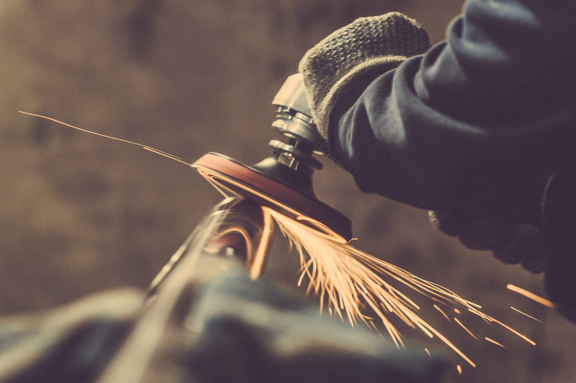 A person is grinding a piece of metal with a grinder.