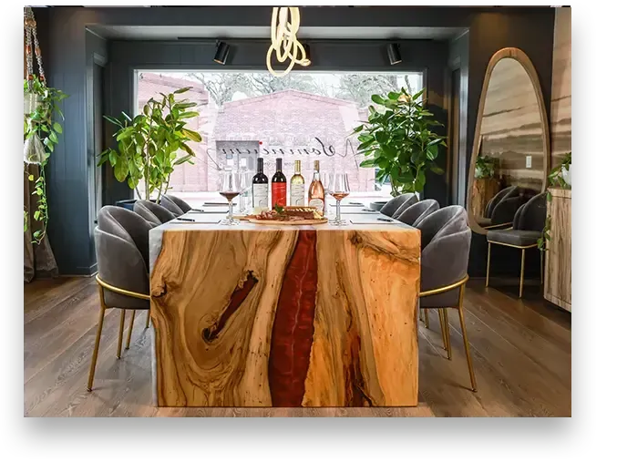 Dining room with wood table, wine bottles, and velvet chairs.