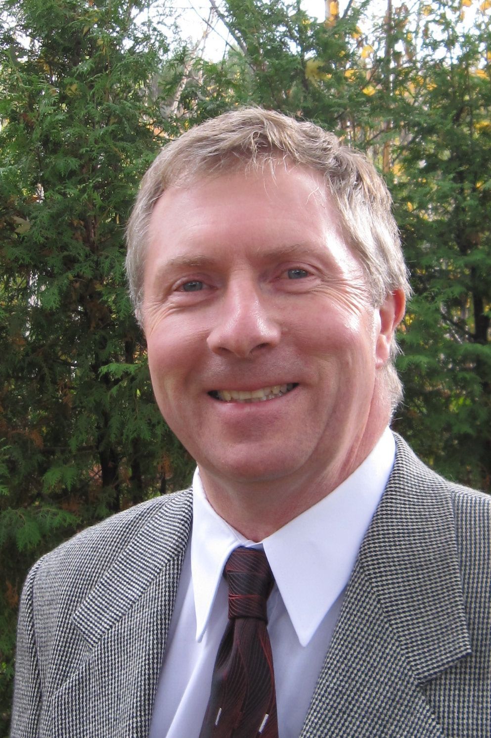 A man in a suit and tie is smiling for the camera