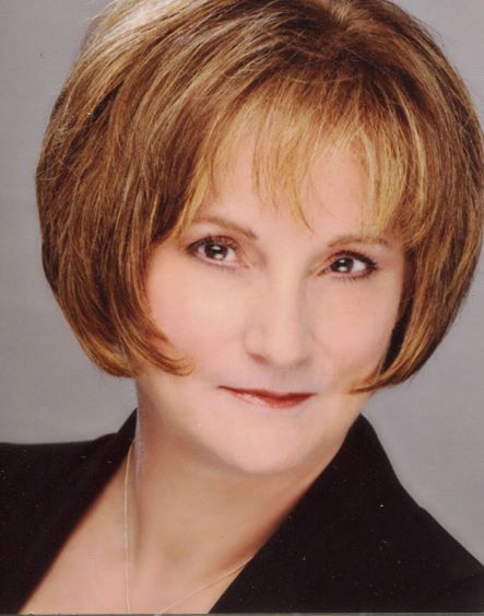 A woman with short brown hair is wearing a black jacket