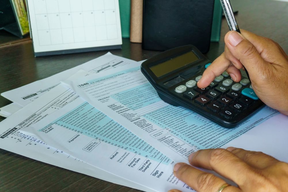 A person is using a calculator while holding a pen.