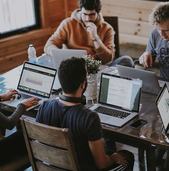 A group of people are sitting at a table with laptops.