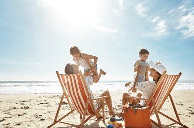 A family is sitting in lawn chairs on the beach.