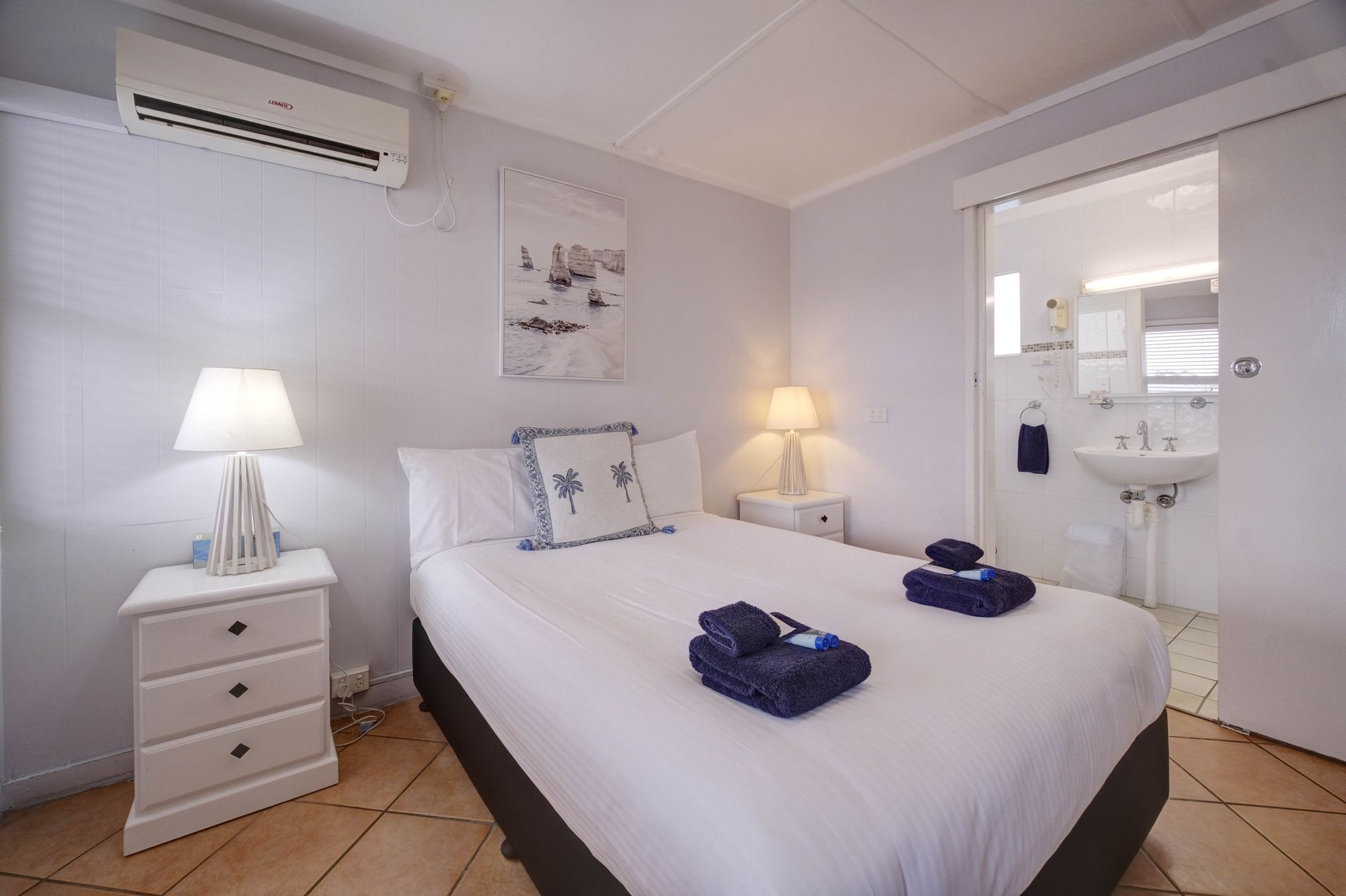 A Bedroom With a Bed, Nightstand, Lamp, Towels and a Bathroom — Bali Hi Motel In Tuncurry, NSW