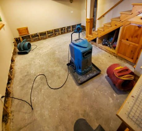 Basement with floor sanding machine, hose, and stairs; unfinished wood floor and tools along the wall