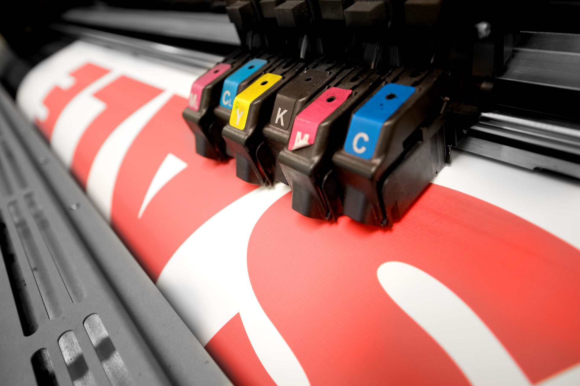 Close-up of a large format printer printing a red and white banner.
